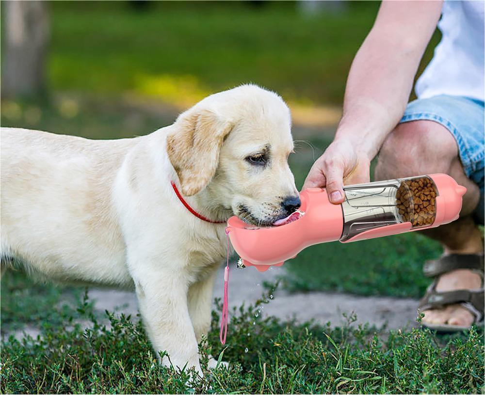 Portable 3-in-1 dog water bottle with attached drinking bowl and garbage bag storage compartment on a soft off-white background