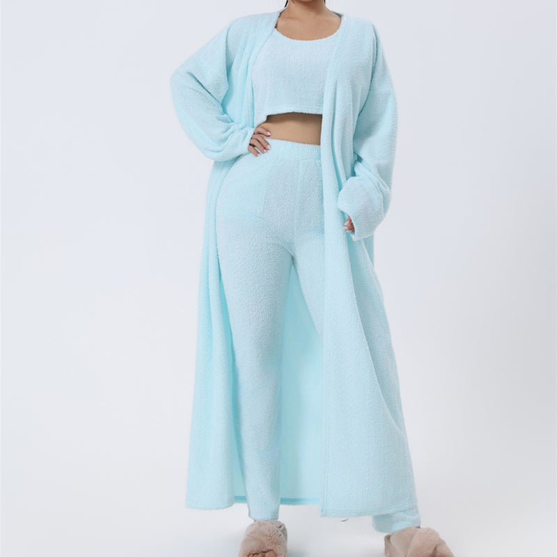 Full-length studio shot of a woman in a matching 3 piece cozy pajama lounge set with top, layering piece and long pants on soft warm-grey backdrop
