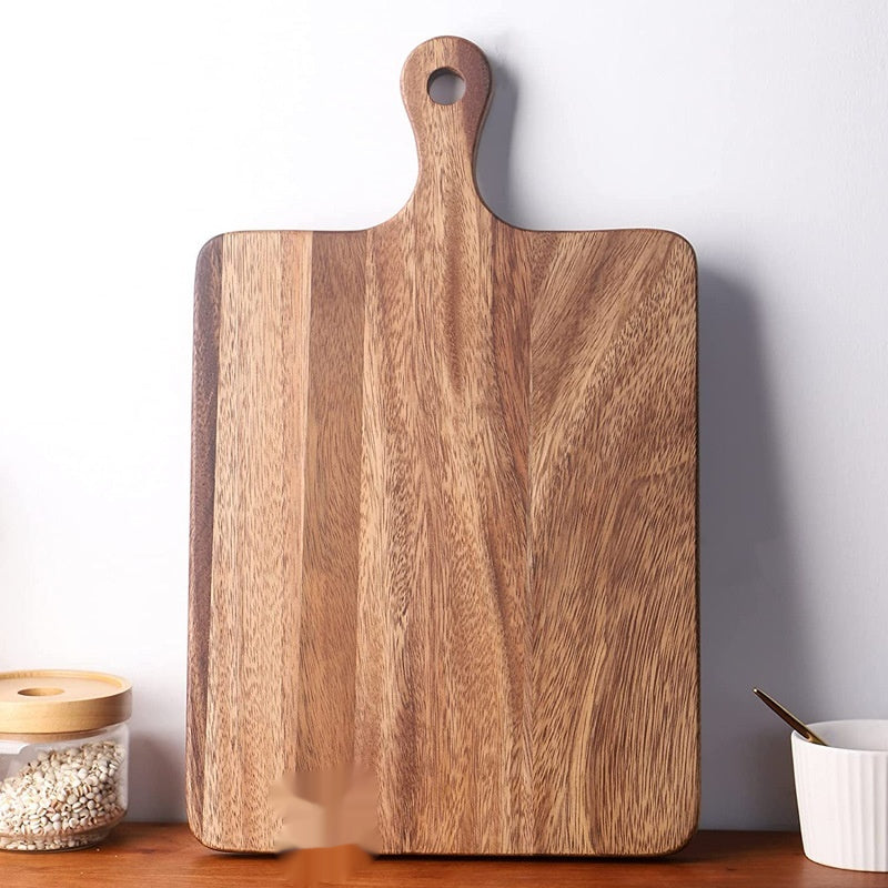 Solid acacia wood cutting board on dark slate, side light catching the grain