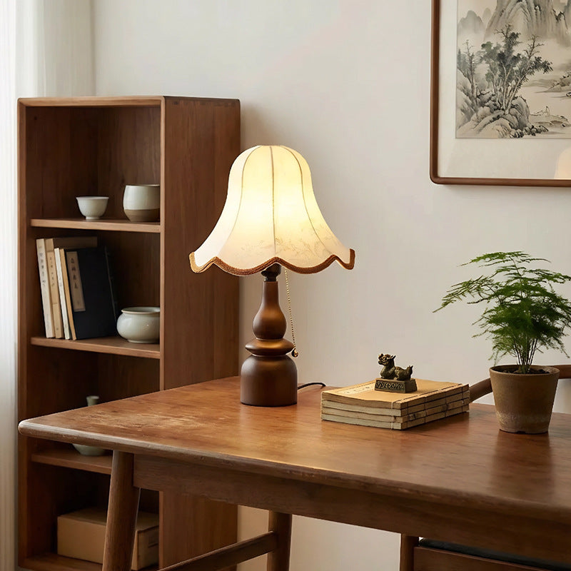 Vintage bedside lamp switched on beside a stack of books and reading glasses